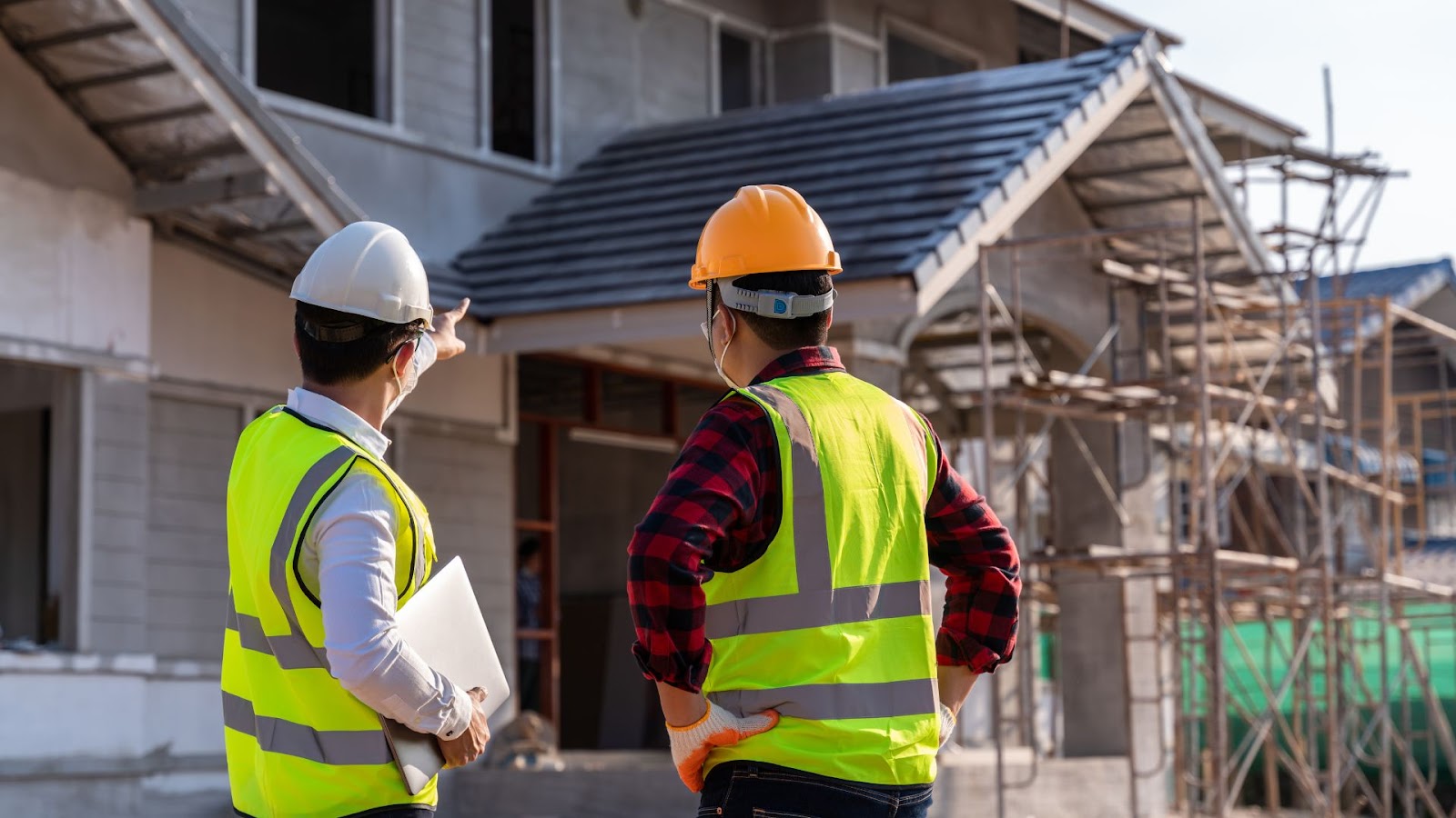 Two construction workers standing in front of a house