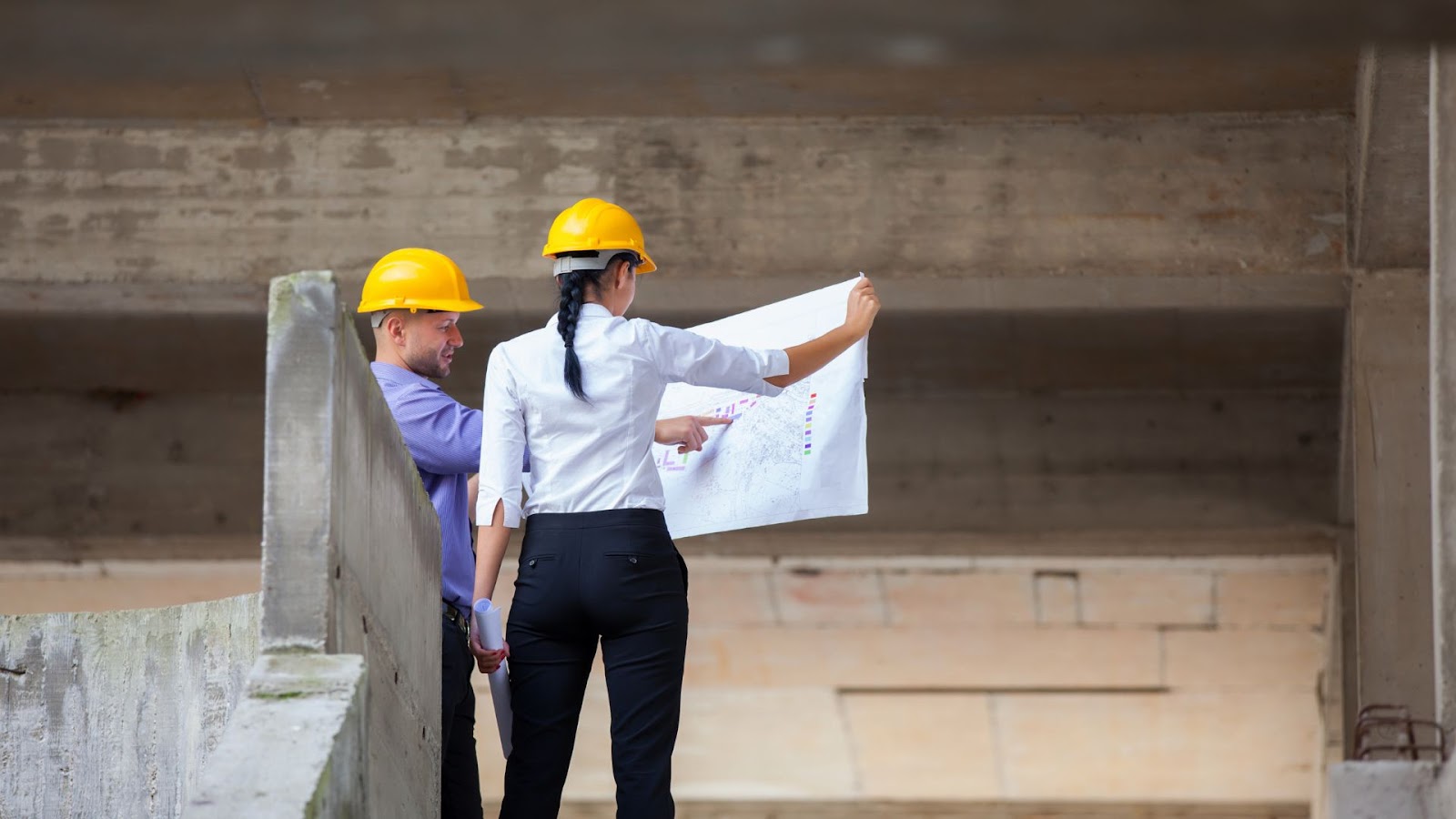 Two people in hard hats looking at a blueprint