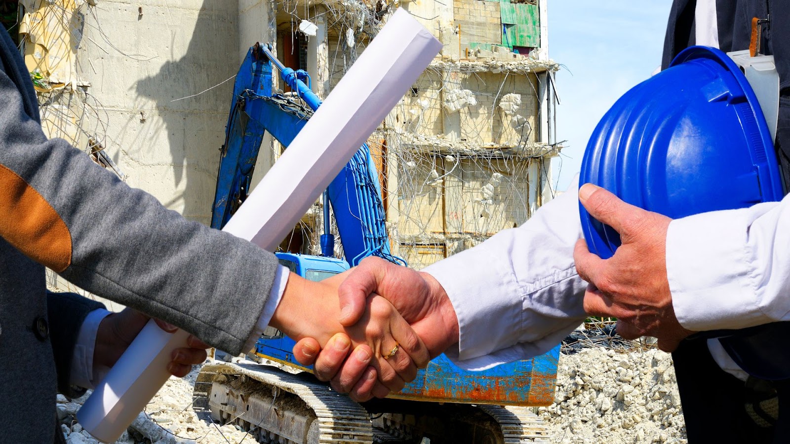 Two people shaking hands in front of a construction site