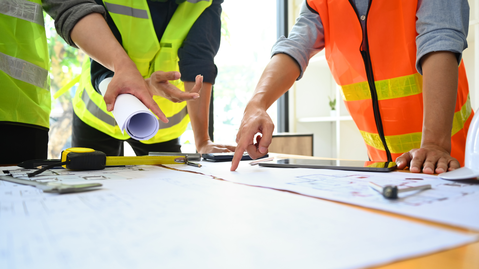 Group of people standing around a table with blueprints.