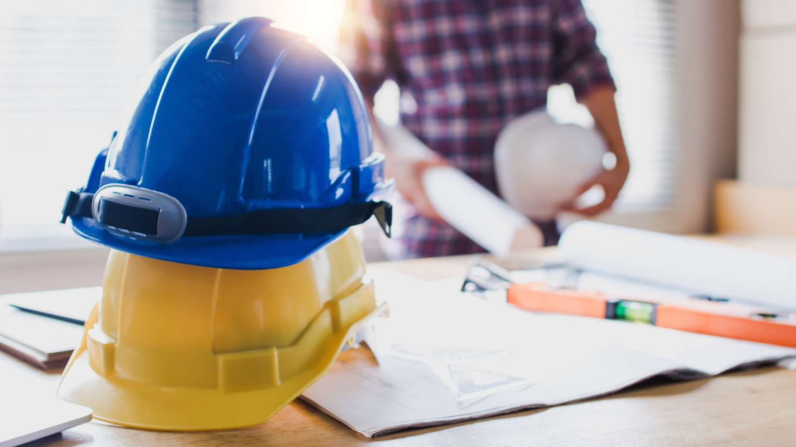 Hard hats on a table with paperwork. 