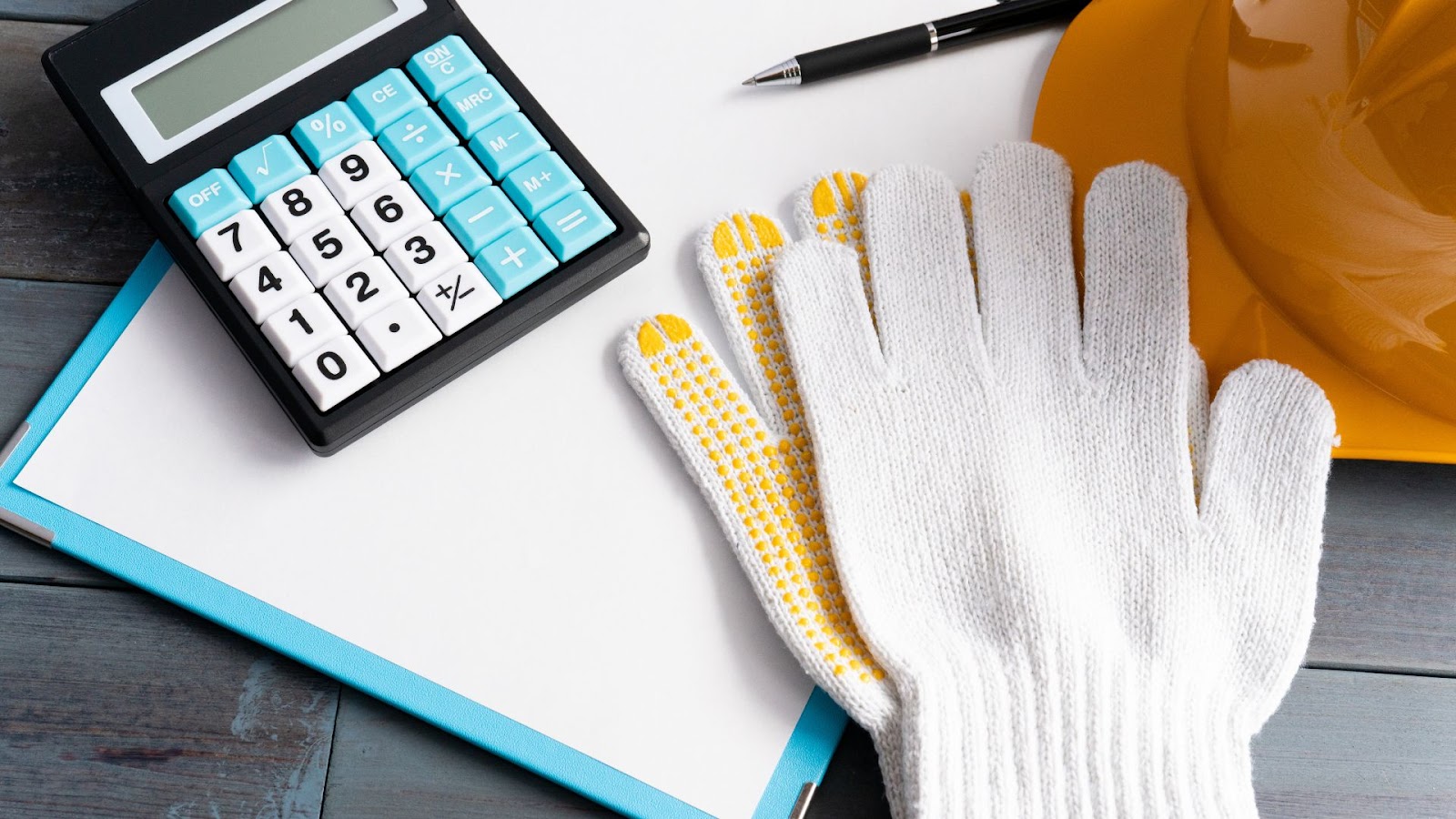 Hard hat, gloves and calculator on a desk