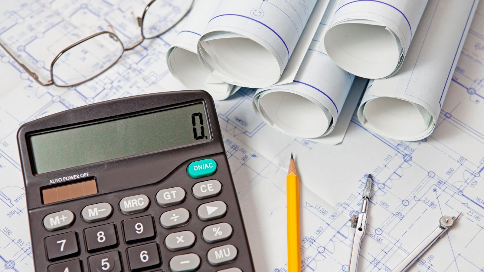 Calculator, glasses, pencils and blueprints on a table