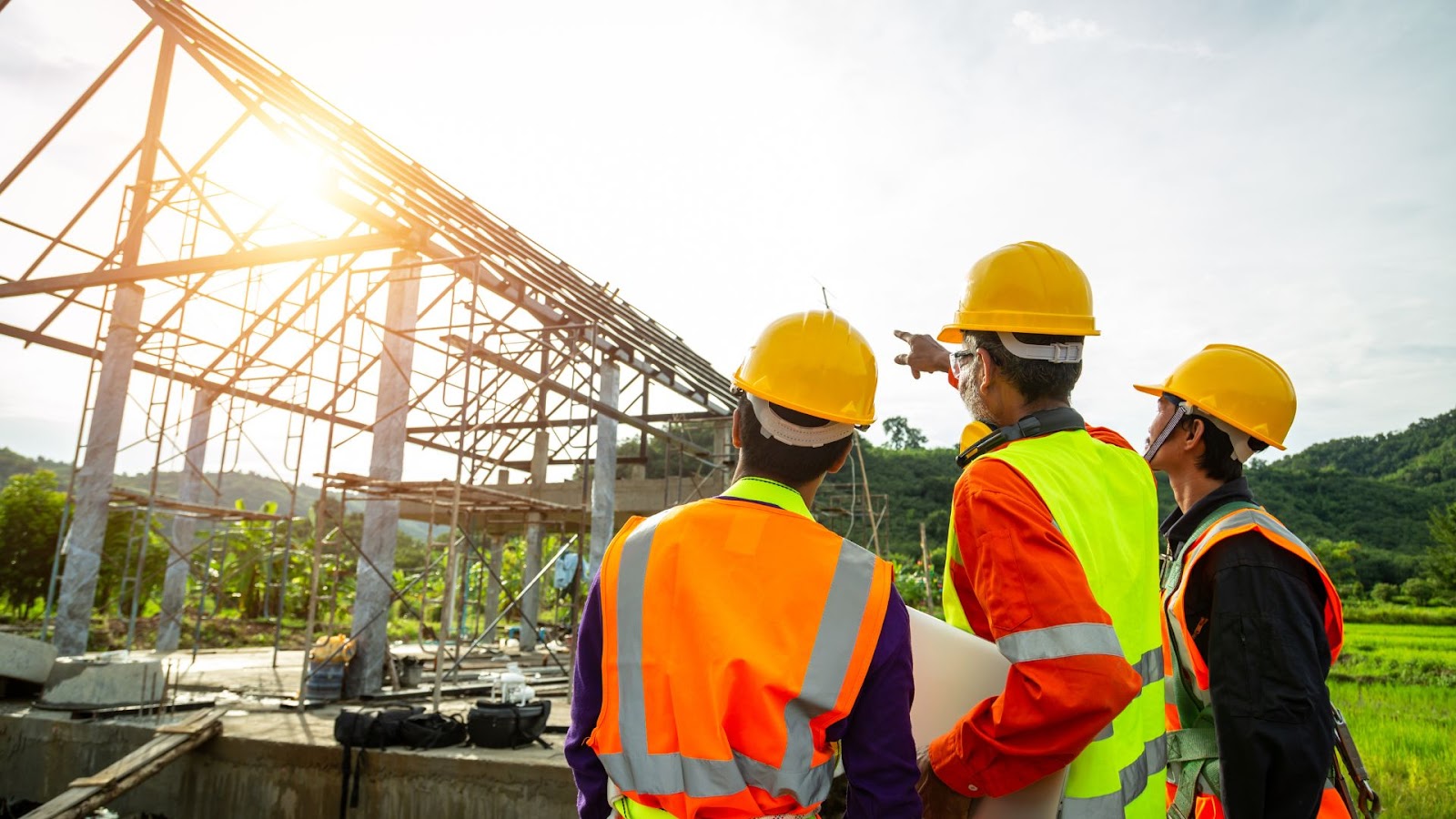 Three construction workers standing in front of a construction site