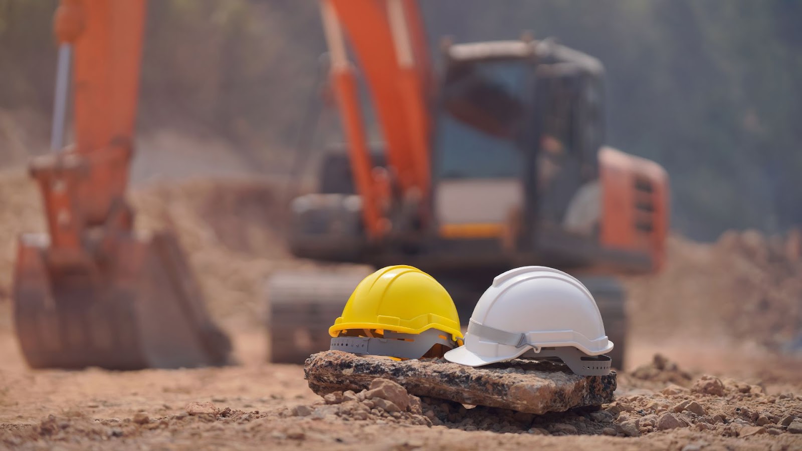 Two hard hats sitting in front of an excavator.