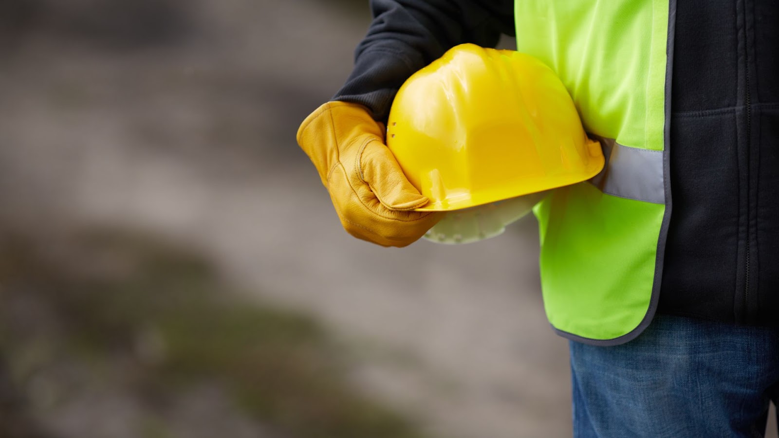 Construction worker holding a yellow hard hat.