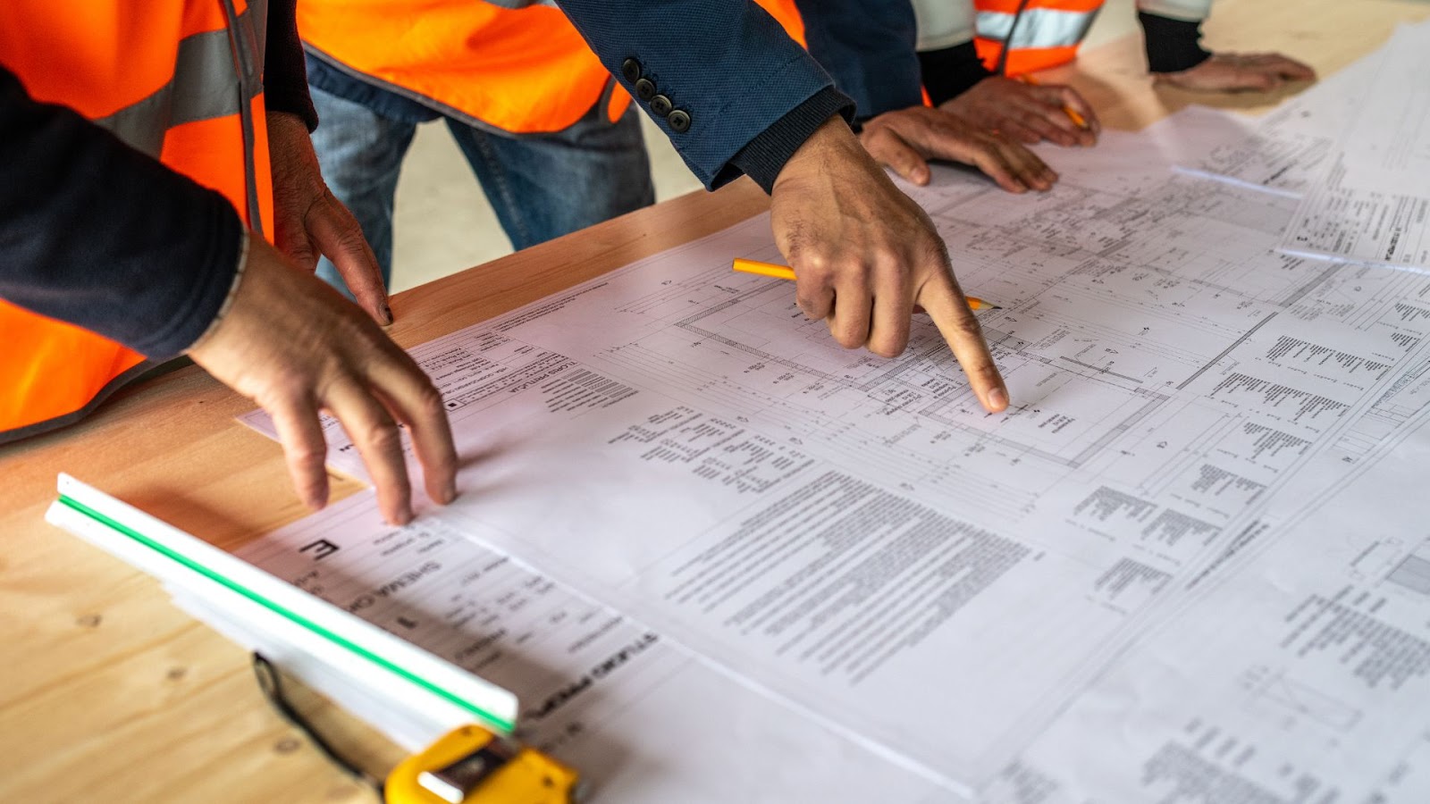 A group of construction workers looking at blueprints on a table