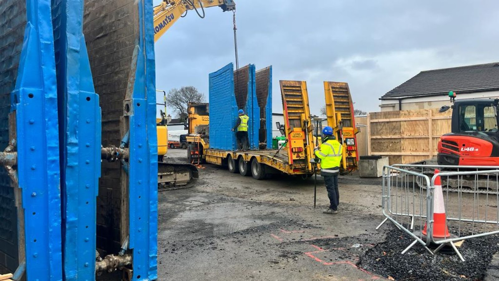 Construction workers loading a large piece of metal into a truck