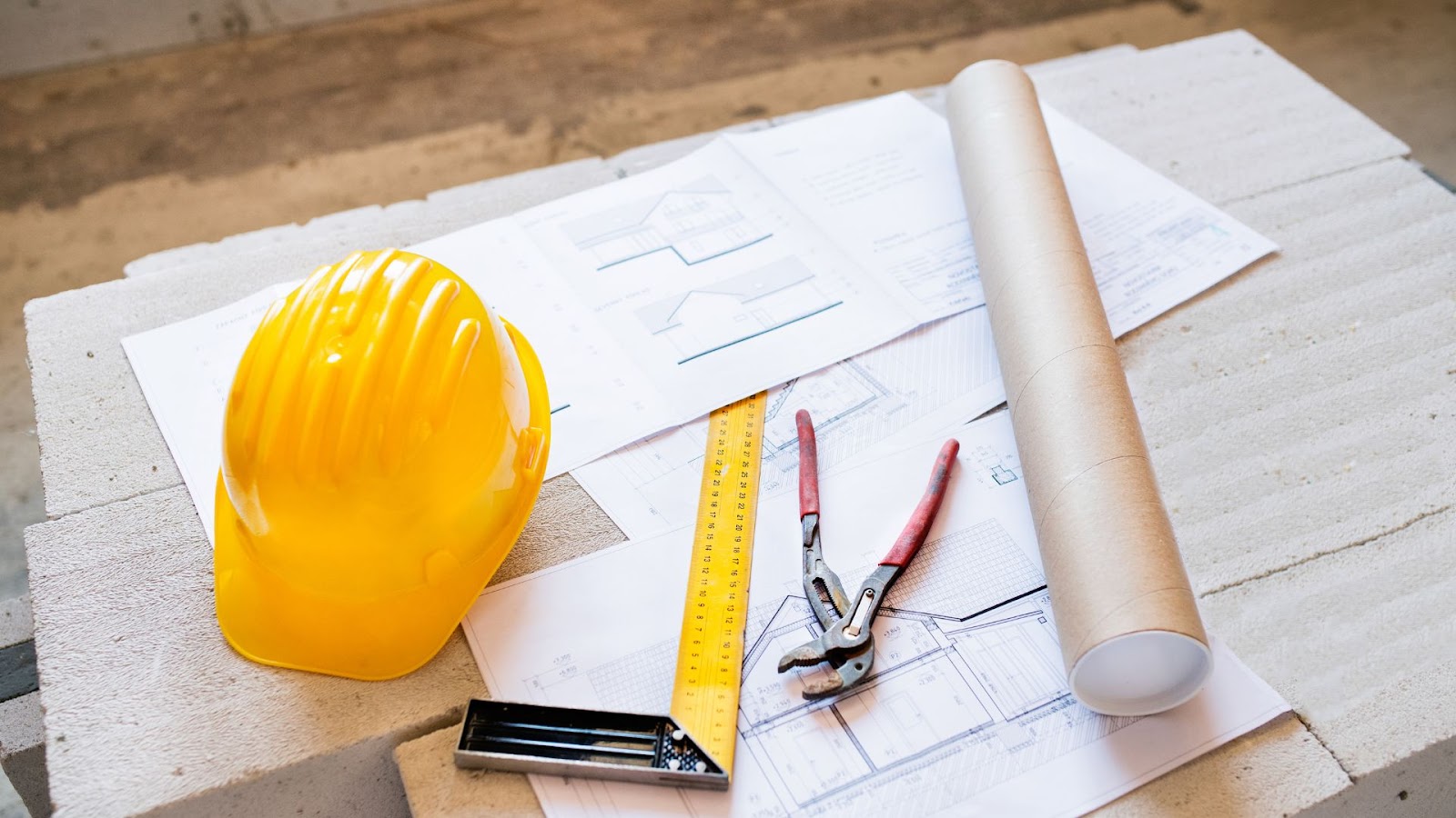 Construction materials on a table with a hard hat and other tools