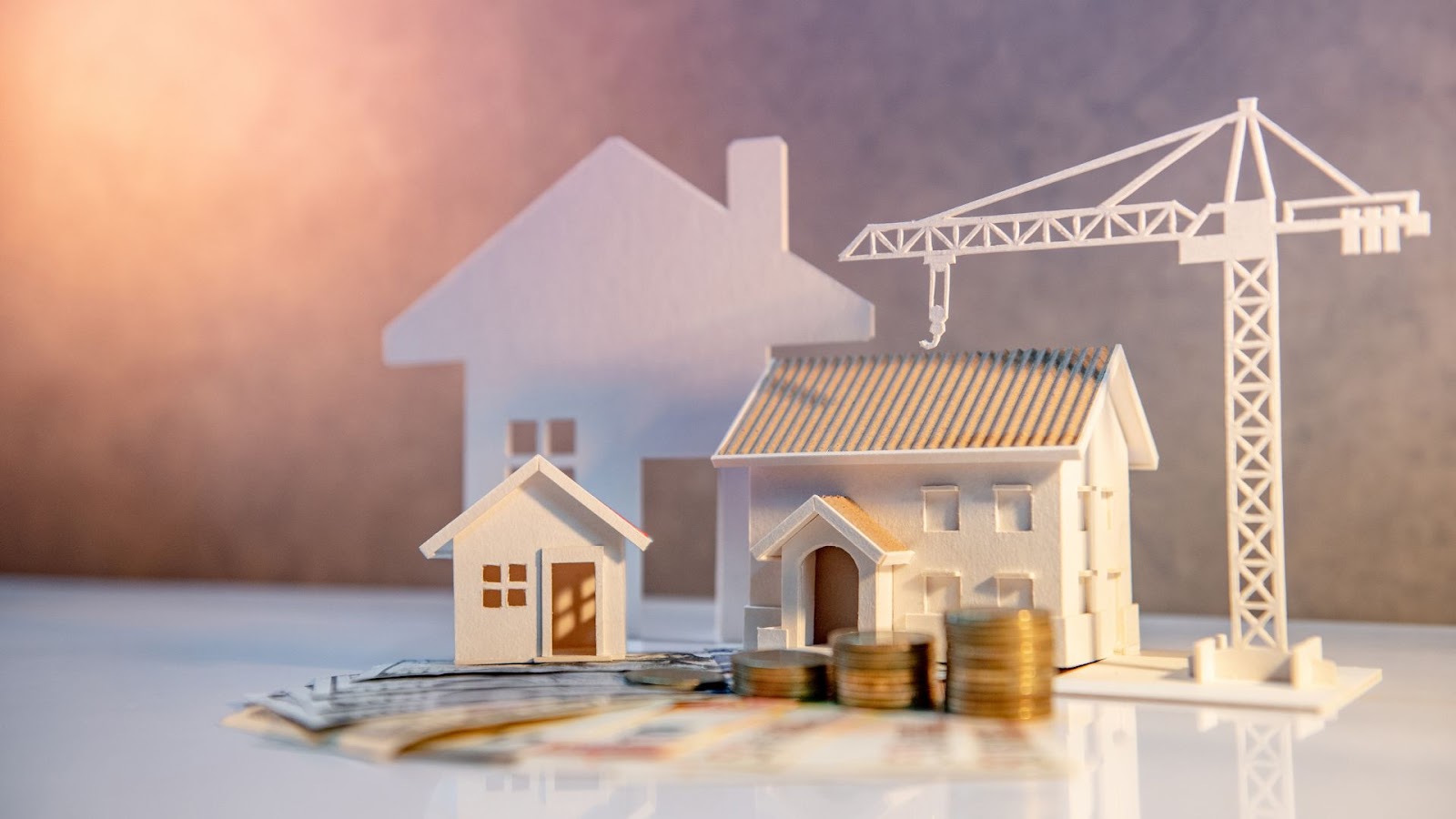 Paper model of house with money and crane on table