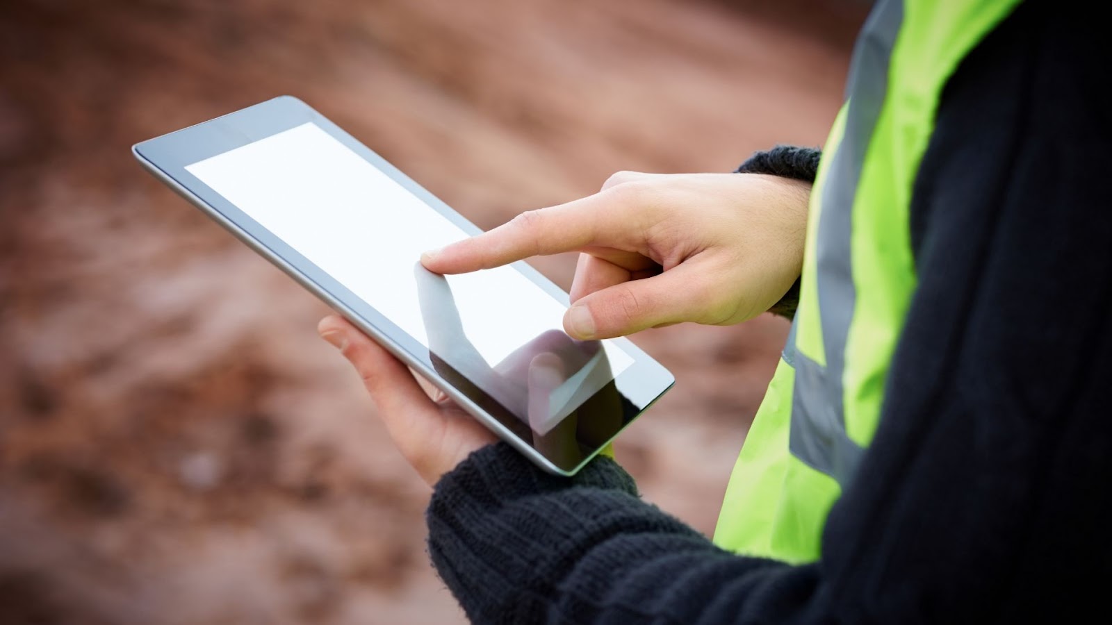 A person in a safety vest holding a tablet computer