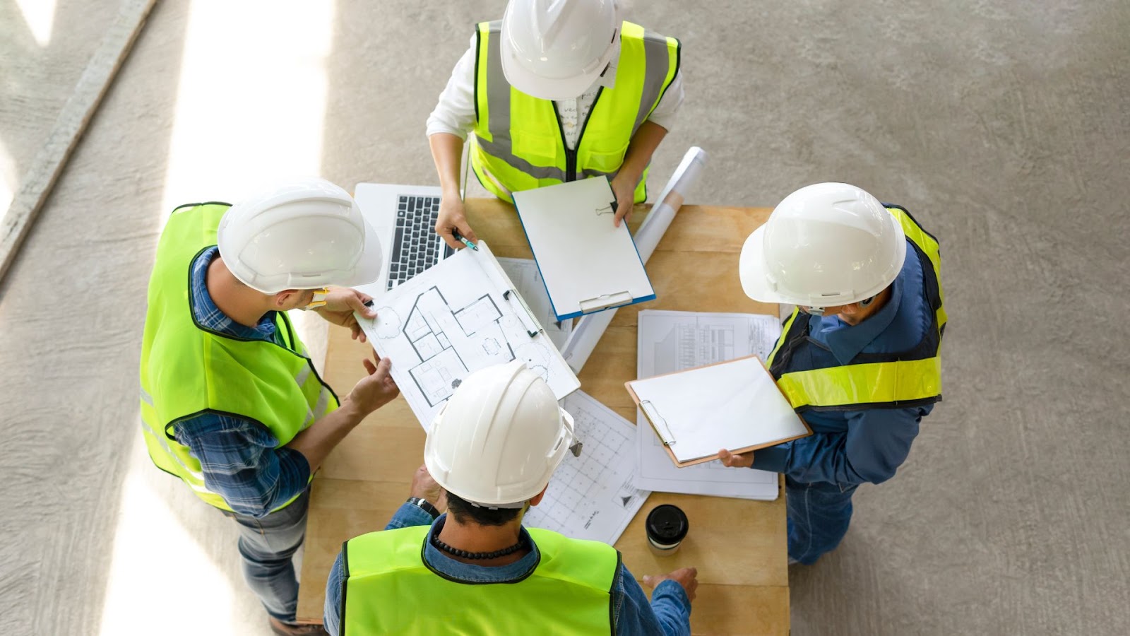 Group of construction workers standing around a table with blueprints