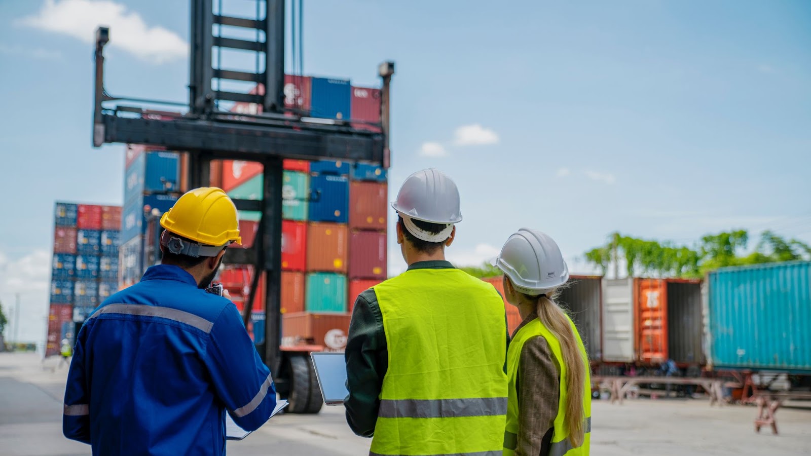 Three people in hard hats standing next to a container truck